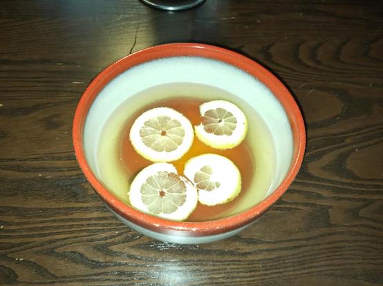 Bowl of punch. Bright yellow liquid with some slices of lemon.